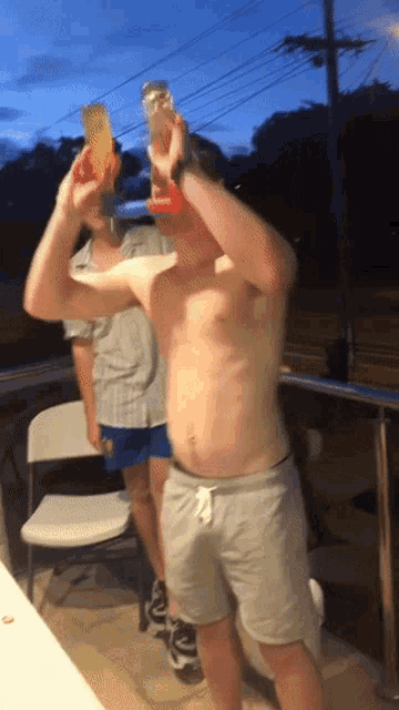 a man without a shirt is holding a bottle of orange juice over his head