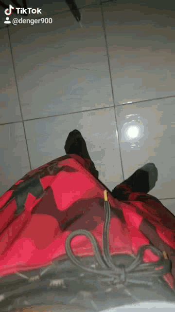 a person wearing red camo shorts and black socks is standing on a tiled floor ..