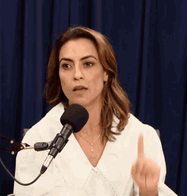 a woman speaking into a microphone with her finger pointing