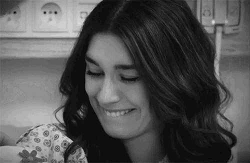 a woman is smiling in a black and white photo while holding a baby in a hospital room .