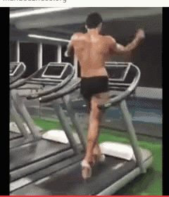 a shirtless man is running on a treadmill in a gym without a shirt on .
