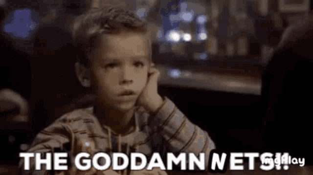 a young boy is sitting at a table with his hand on his face and the words `` the goddamn nets '' written in the foreground