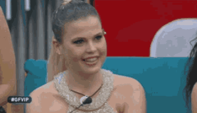 a woman in a gold dress is sitting on a blue couch smiling .