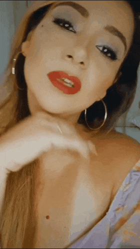 a woman wearing red lipstick and hoop earrings is making a funny face .