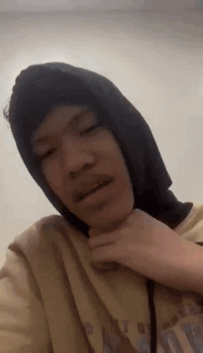 a man wearing a black hoodie and a yellow shirt is taking a picture of himself .