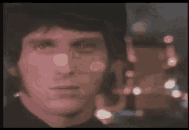 a close up of a man 's face with a blurred background of lights .