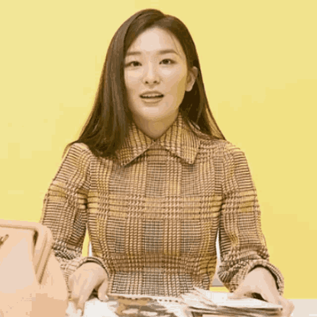 a woman in a plaid shirt sits at a table