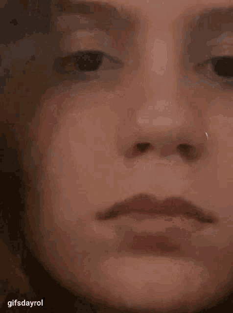 a close up of a woman 's face with a nose ring on her nose .