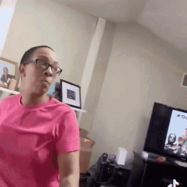 a woman in a pink shirt stands in front of a tv