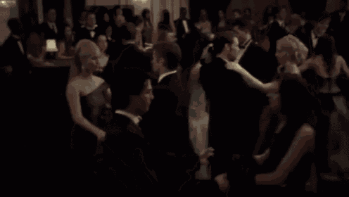 a woman in a white dress is dancing in a crowd of people at a party .
