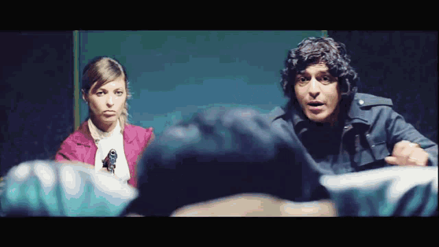 a man and a woman are standing next to each other and one of them is holding a gun
