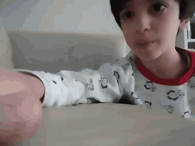 a young boy wearing a white shirt with pandas on the sleeves