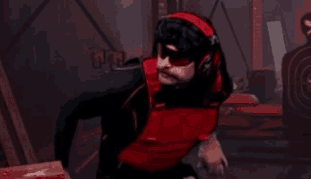 a man wearing a red vest and a black shirt is standing in a dark room