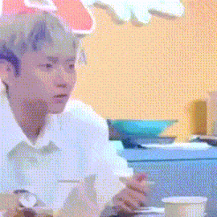 a man in a white shirt is sitting at a table eating food with a fork and spoon .