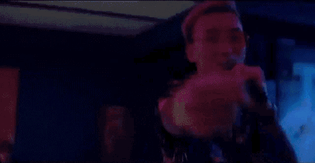 a man with pink hair is singing into a microphone in a room .