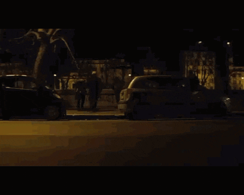 a man in a suit and tie is walking down a street at night