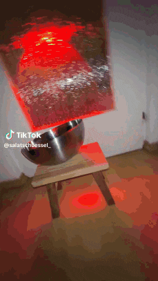 a tiktok video of a bowl on a stool with a red light behind it