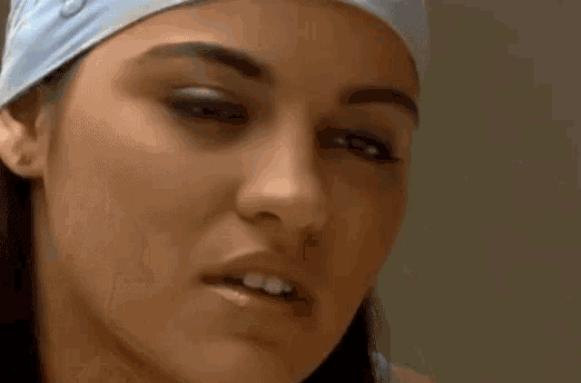 a woman with a bandana on her head is looking at herself in a mirror .