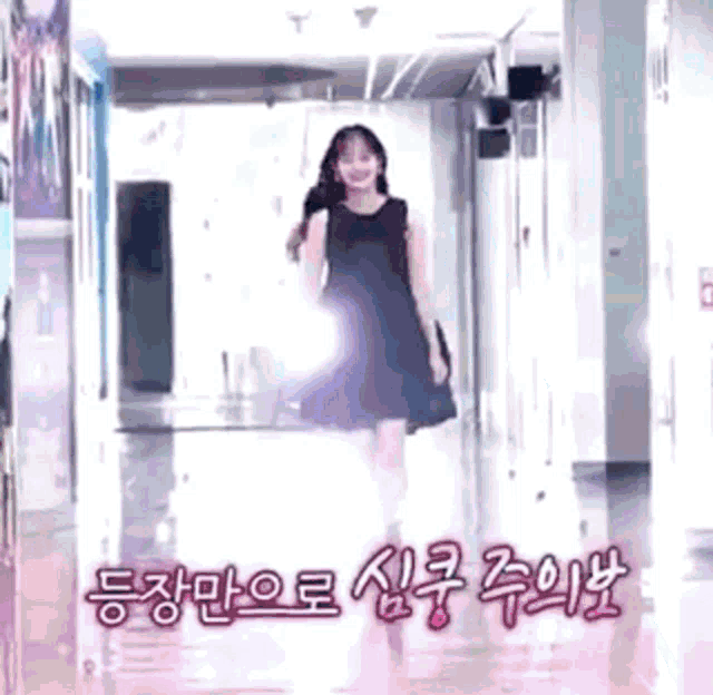 a woman in a black dress is walking down a hallway with chinese writing on the floor .