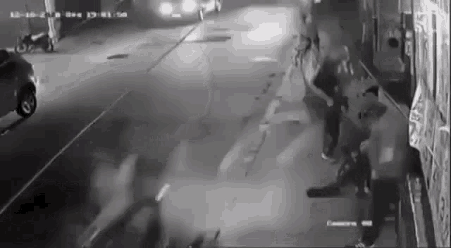 a group of people are standing on the side of a street at night .