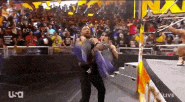 a man is carrying a woman in his arms on a wrestling mat .
