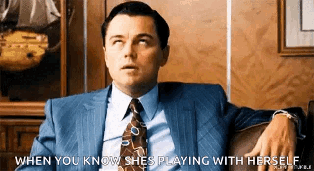 a man in a suit and tie is sitting on a couch and saying when you know she is playing with herself .