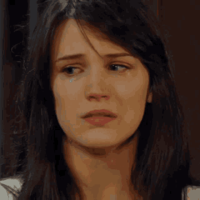 a woman is crying with a tear coming out of her eye .