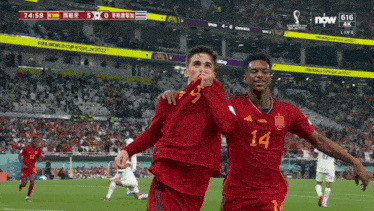 two soccer players one with the number 14 on their jersey