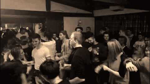a black and white photo of a crowd of people dancing at a party