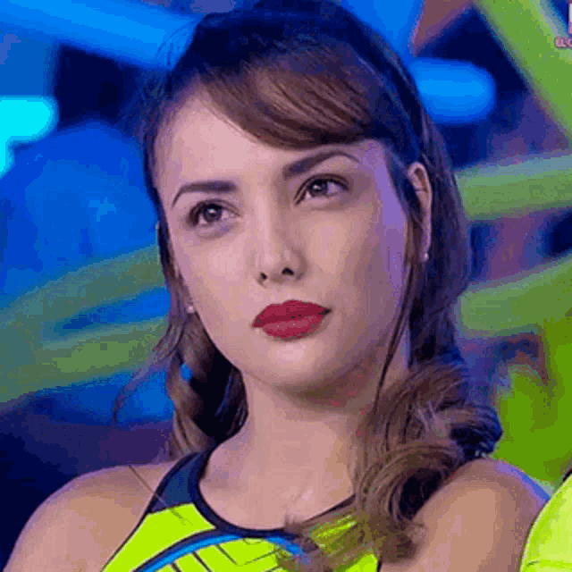 a close up of a woman 's face with a yellow tank top on .