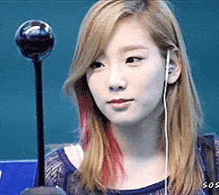 a woman with blonde hair and red highlights is wearing earphones and holding a microphone .