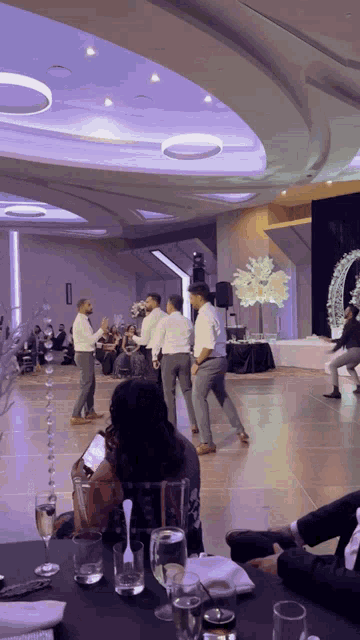 a group of men are dancing in a large ballroom