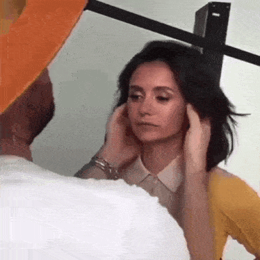 a man is touching a woman 's face with his hands while she looks at the camera .