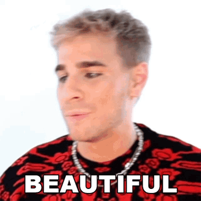 a young man wearing a red and black sweater and a chain around his neck is making a funny face .