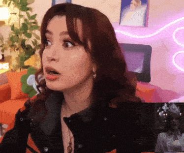 a woman with red hair looks surprised in front of a sign that says ' sg ' on it