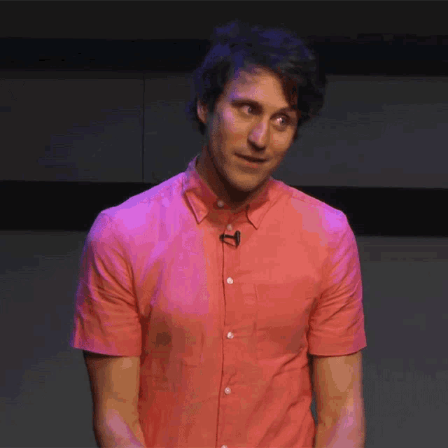 a man wearing a pink shirt has a microphone on his shirt
