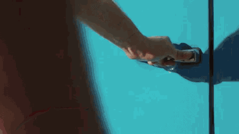 a close up of a person 's hand opening a blue door