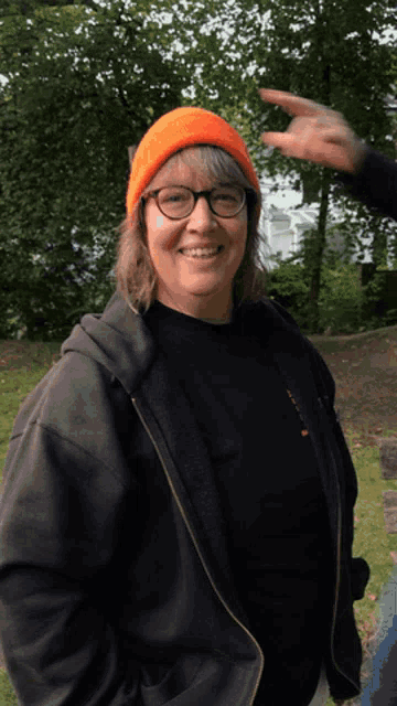 a woman wearing a black shirt and an orange hat is smiling