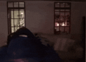 a man with a beard and headphones is standing in front of a window .