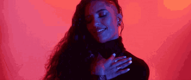 a woman with a shaved head is smiling with her eyes closed and her hands on her chest .