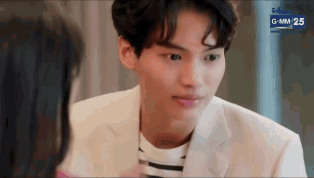a young man in a suit is looking at a woman in a striped shirt .