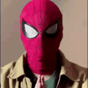 a man wearing a red spider-man mask and a jacket is praying .