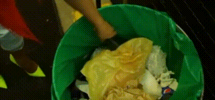 a person is throwing trash into a green trash can with a pepsi logo on the side .