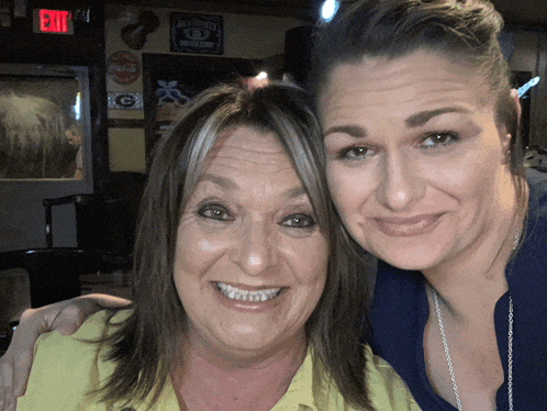 two women pose for a picture in front of a jack daniels sign
