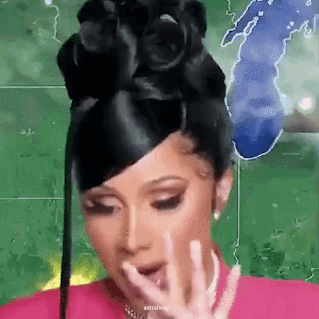a woman with black hair in a bun is covering her mouth with her hand .