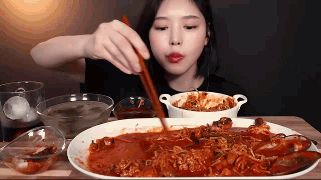 a woman is eating food with chopsticks from a plate