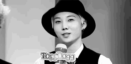 a black and white photo of a young man wearing a hat and a vest .
