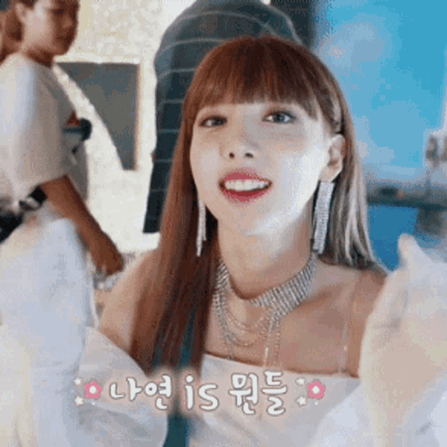 a woman wearing a white top and a necklace is smiling in a room .