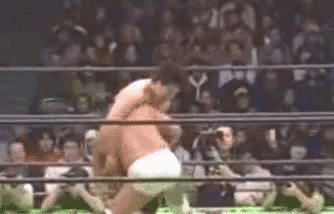 a man is laying on the ground in a boxing ring while a referee looks on .