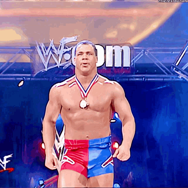 a shirtless wrestler with a medal around his neck stands in front of a sign that says w dm